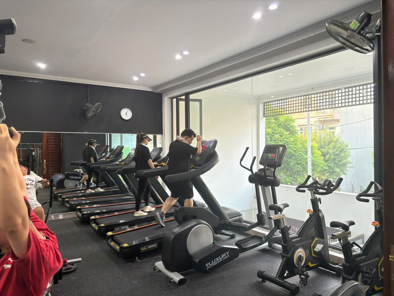 Dãy máy chạy bộ và xe đạp tập cạnh cửa kính